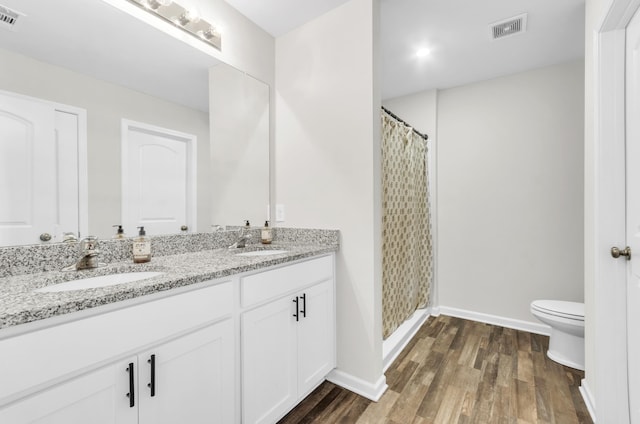 bathroom with toilet, wood finished floors, a sink, and visible vents