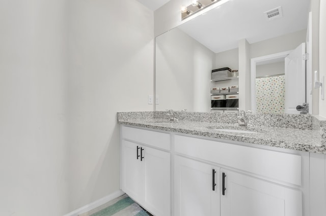 full bathroom featuring double vanity, a sink, visible vents, and baseboards