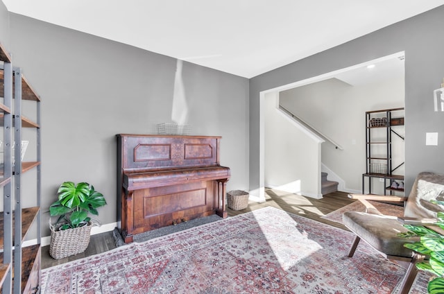 living area with stairway, baseboards, and wood finished floors