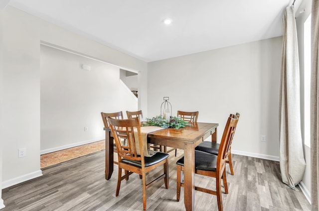 dining area featuring baseboards, wood finished floors, and recessed lighting