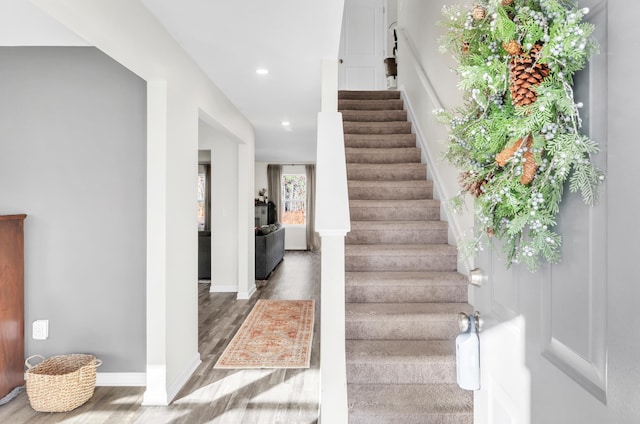 staircase with baseboards, wood finished floors, and recessed lighting