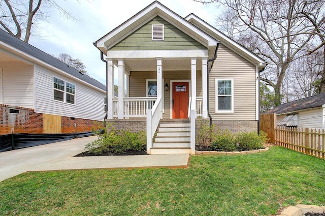 view of front of house with a porch, a front yard, brick siding, and fence