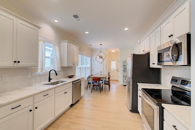 kitchen featuring stainless steel appliances, visible vents, light wood-style flooring, white cabinetry, and a sink