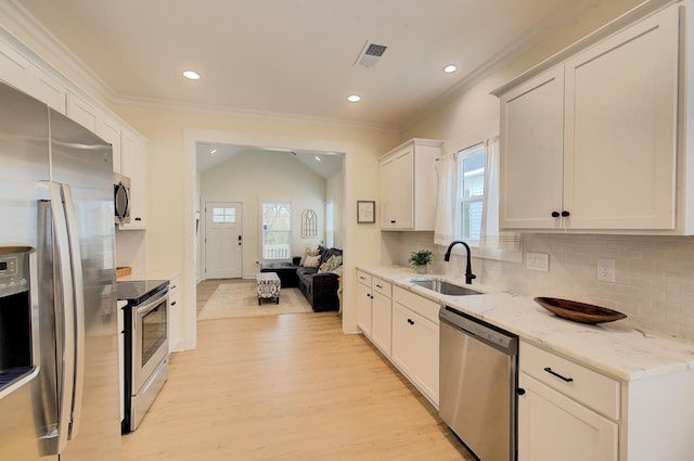 kitchen with crown molding, visible vents, appliances with stainless steel finishes, a sink, and light wood-type flooring