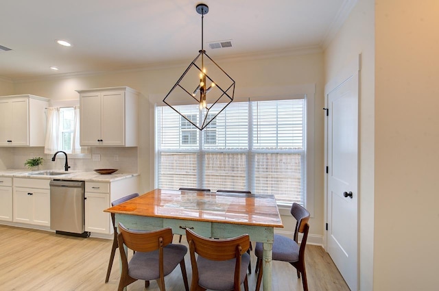 dining room featuring a chandelier, ornamental molding, visible vents, and light wood-style floors