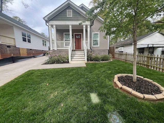 shotgun-style home with covered porch, a front yard, and fence