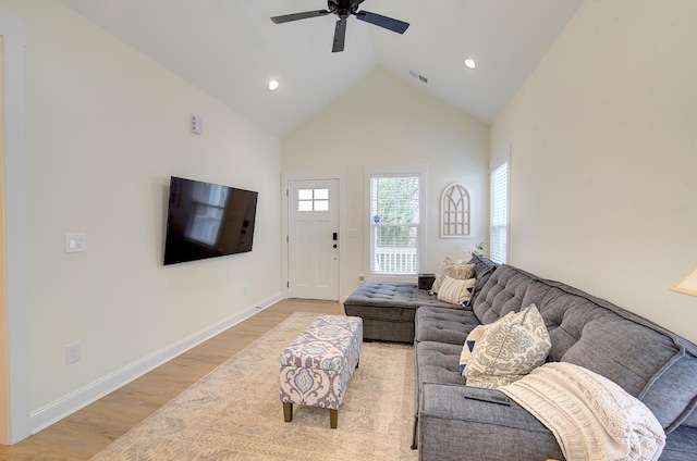 living area with baseboards, visible vents, ceiling fan, light wood-style floors, and high vaulted ceiling