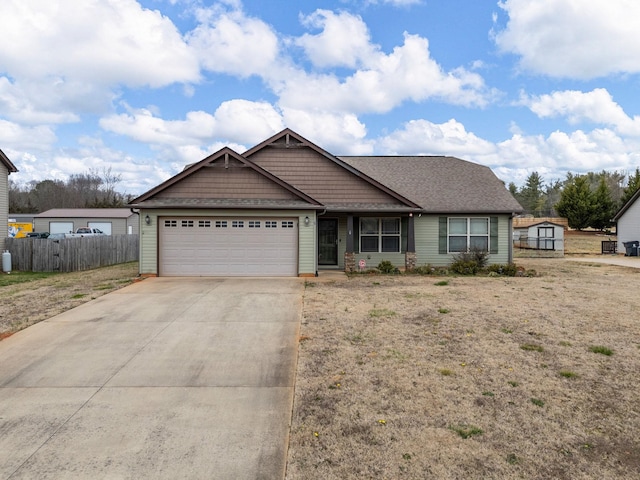 view of front of property featuring a garage, concrete driveway, a storage shed, and fence