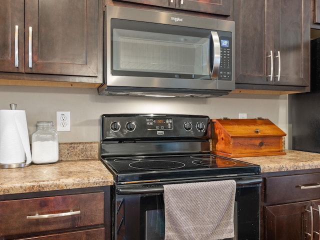 kitchen featuring dark brown cabinetry, black / electric stove, light countertops, and stainless steel microwave