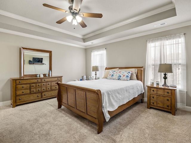 carpeted bedroom featuring visible vents, a tray ceiling, and crown molding