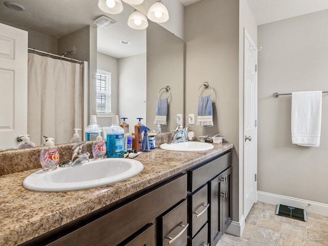 full bath with visible vents, a sink, baseboards, and double vanity