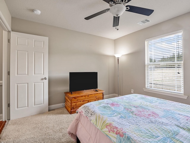 bedroom featuring carpet floors, visible vents, a ceiling fan, a textured ceiling, and baseboards