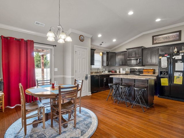 dining space with lofted ceiling, crown molding, visible vents, and wood finished floors