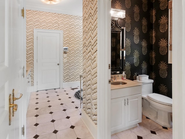 bathroom with toilet, wallpapered walls, crown molding, and vanity