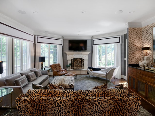 living room with ornamental molding, a fireplace with raised hearth, and plenty of natural light