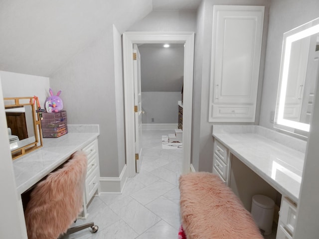 bathroom featuring lofted ceiling, marble finish floor, and baseboards