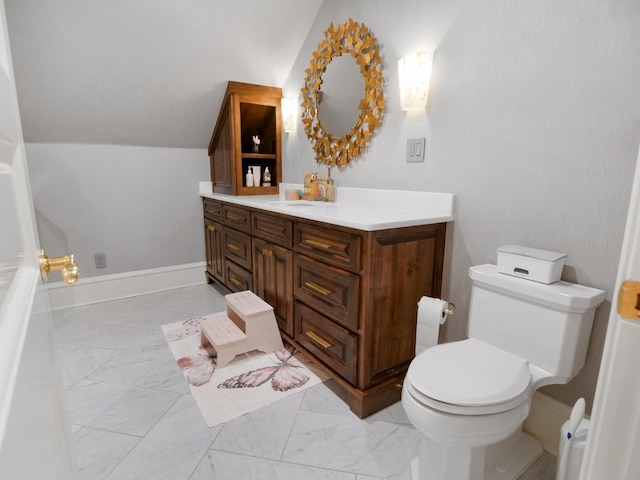 bathroom featuring baseboards, toilet, lofted ceiling, marble finish floor, and vanity