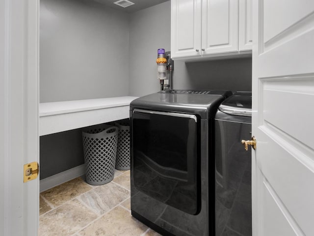 laundry area with visible vents, separate washer and dryer, cabinet space, and baseboards