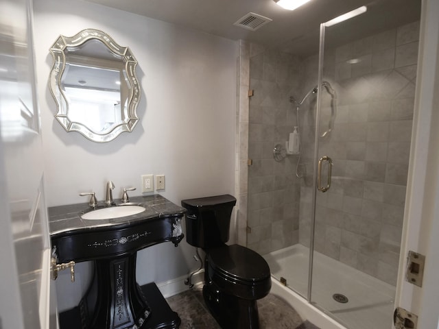 bathroom featuring toilet, a sink, visible vents, and a shower stall