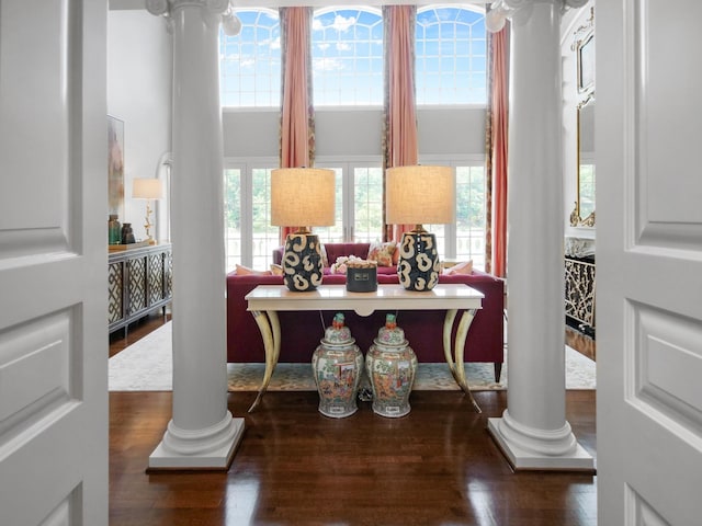 office with a towering ceiling, wood finished floors, and decorative columns