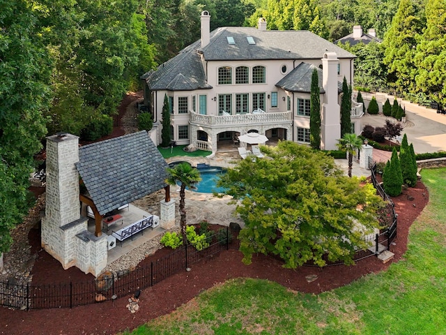 back of property with a chimney, stucco siding, a patio area, a balcony, and a fenced backyard