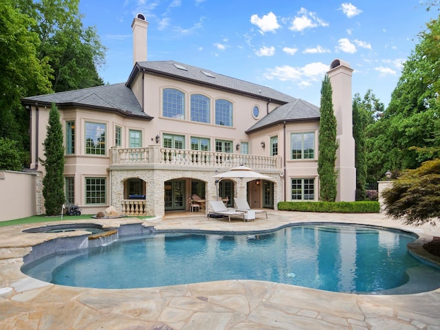 back of property featuring stone siding, french doors, a patio, and a chimney