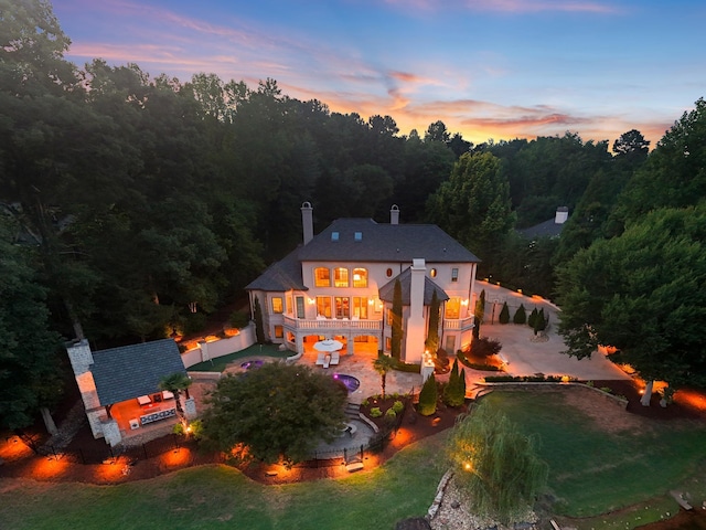 rear view of house with a patio, a chimney, and a view of trees