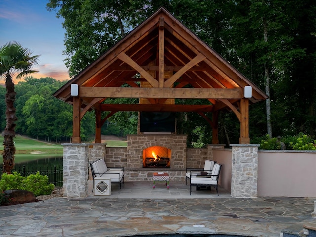 view of patio / terrace featuring a gazebo, an outdoor stone fireplace, and fence