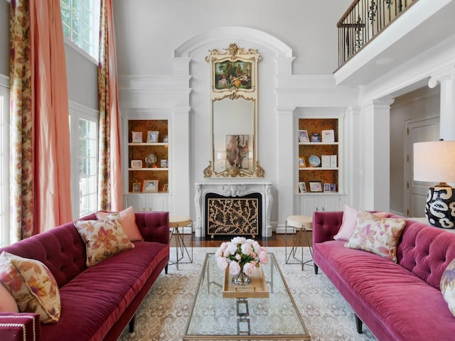 sitting room featuring a towering ceiling, a fireplace, built in features, and wood finished floors