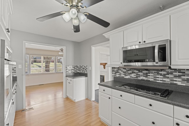 kitchen with white cabinetry, dark countertops, stainless steel microwave, and black electric cooktop