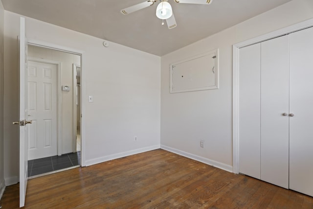 unfurnished bedroom featuring ceiling fan, a closet, wood-type flooring, and baseboards