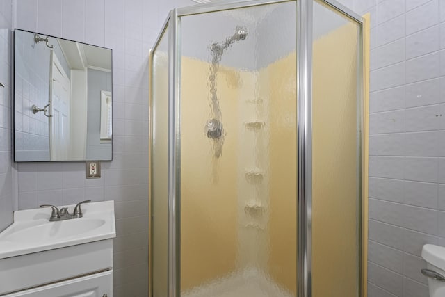 bathroom with toilet, a stall shower, vanity, and tile walls