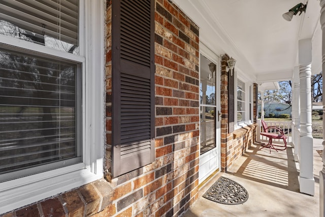 view of exterior entry with covered porch and brick siding