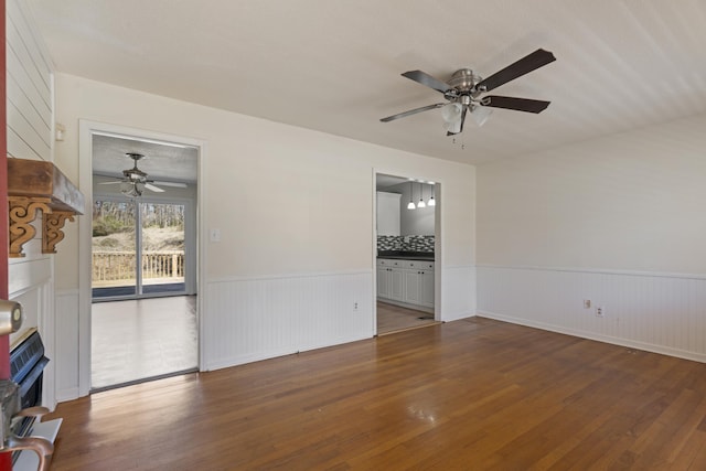 empty room featuring a ceiling fan, wainscoting, and hardwood / wood-style floors