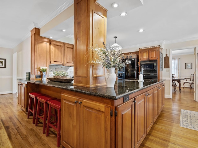 kitchen featuring ornamental molding, dark stone countertops, backsplash, and light wood-style flooring