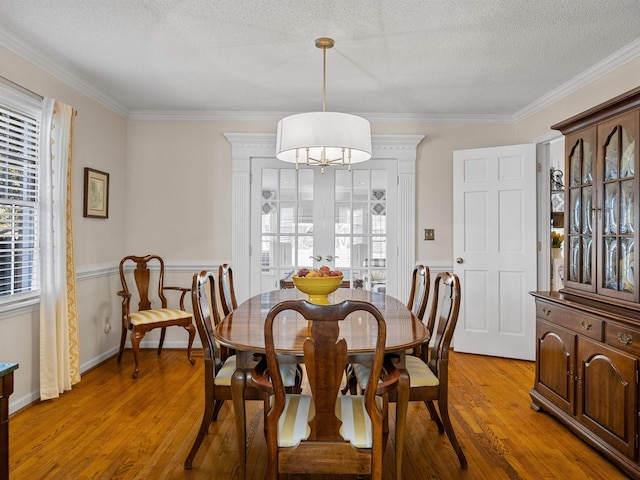 dining area featuring french doors, light wood finished floors, ornamental molding, a textured ceiling, and baseboards