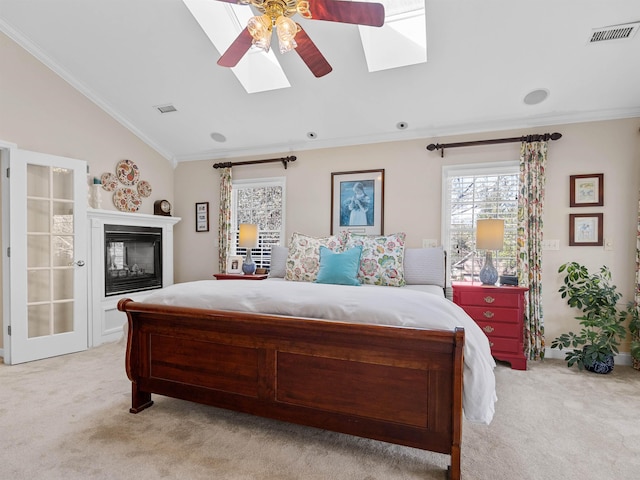 bedroom with lofted ceiling with skylight, light colored carpet, visible vents, and ornamental molding