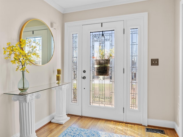 entrance foyer featuring baseboards, visible vents, wood finished floors, crown molding, and ornate columns