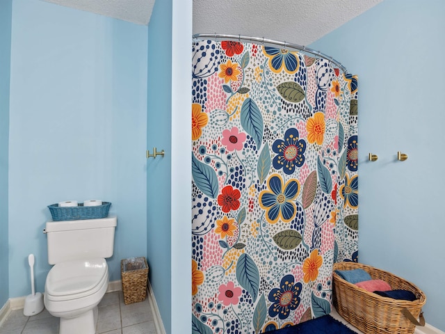 bathroom with toilet, baseboards, a textured ceiling, and tile patterned floors