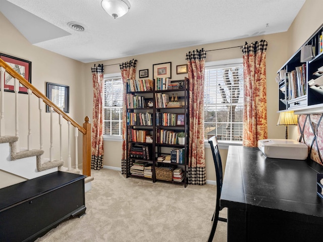 carpeted office space with visible vents, a textured ceiling, baseboards, and a wealth of natural light