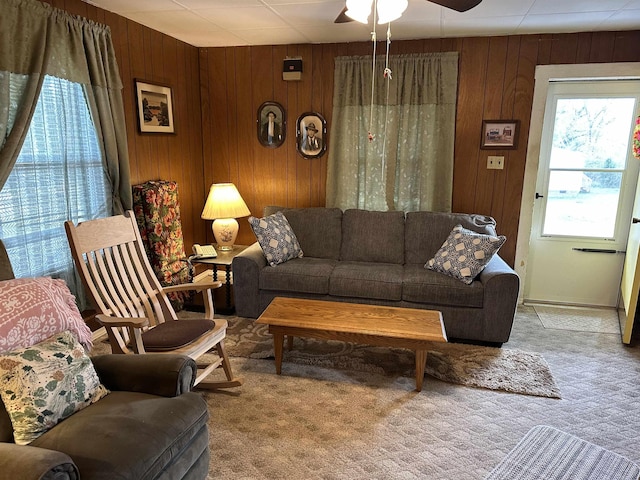 carpeted living area featuring wood walls and a ceiling fan