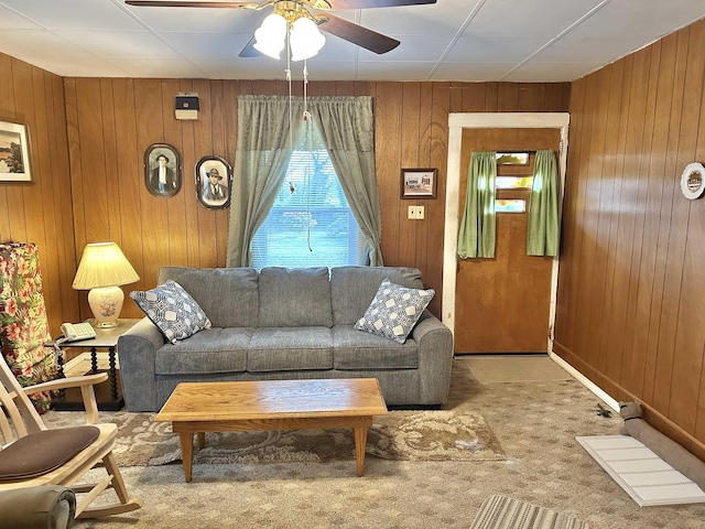 living room with carpet floors, wooden walls, and a ceiling fan