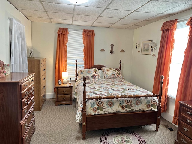 bedroom featuring light carpet, a drop ceiling, and visible vents