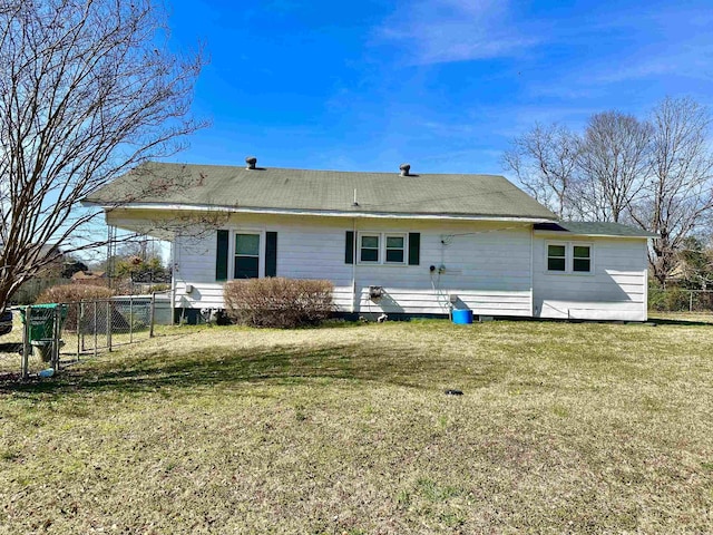 rear view of house with a lawn and fence