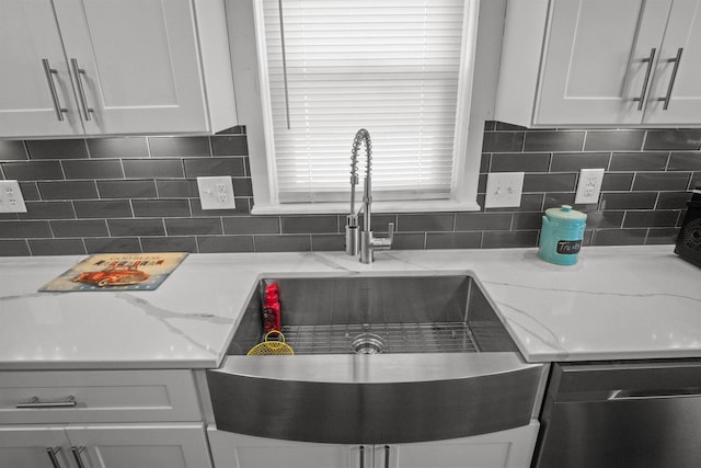 kitchen with a sink, white cabinetry, backsplash, light stone countertops, and dishwasher