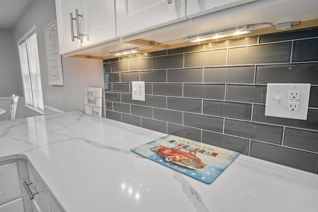 interior details featuring white cabinets and light stone countertops