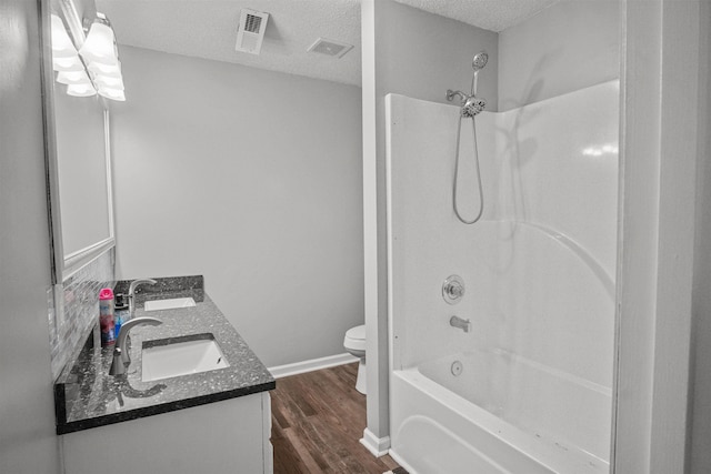 full bathroom featuring a textured ceiling, visible vents, a sink, and wood finished floors