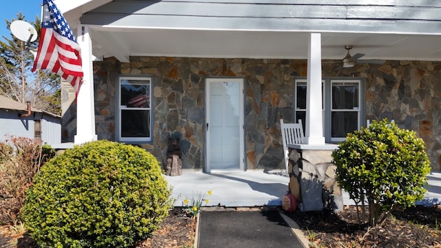 view of exterior entry with covered porch and stone siding