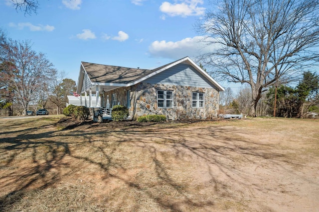 view of side of property featuring stone siding and a lawn