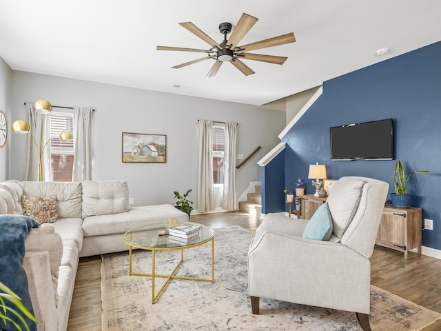 living room with wood finished floors, visible vents, ceiling fan, and stairs